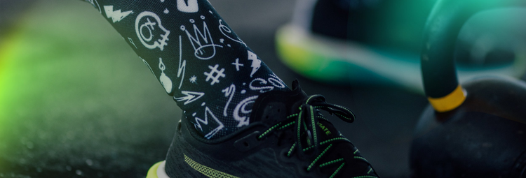 Close-up of a person's foot wearing a black athletic shoe with green accents, stepping on a green object.